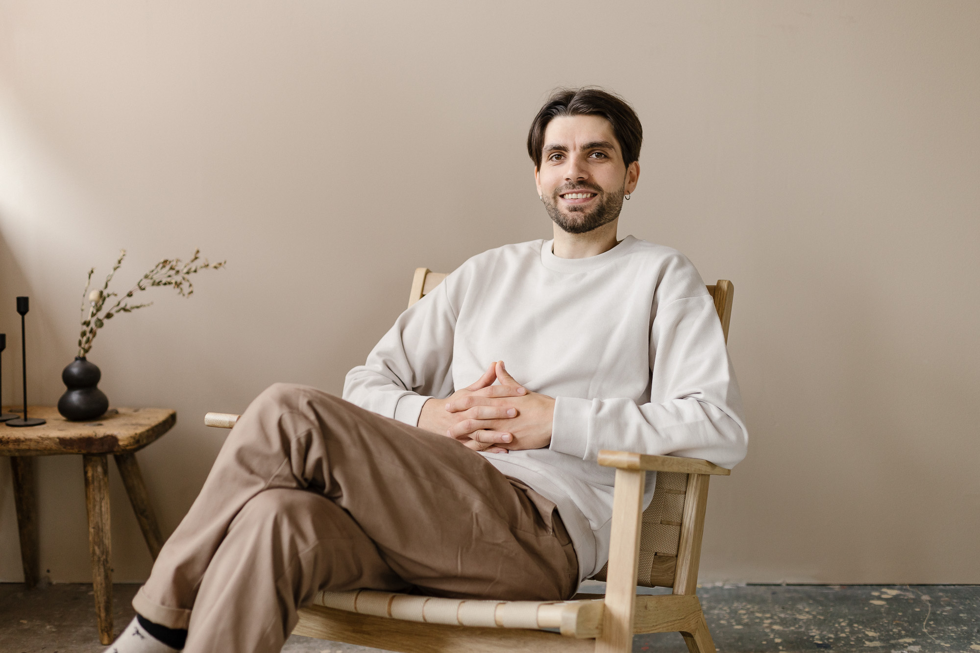 Picture of Artome's own designer Joel Hautala who sits on the chair and smiles to the camera.